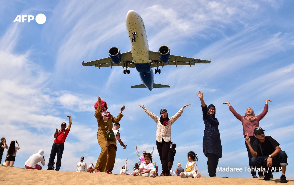 tourists on Mai Khao Beach with a plane who lands